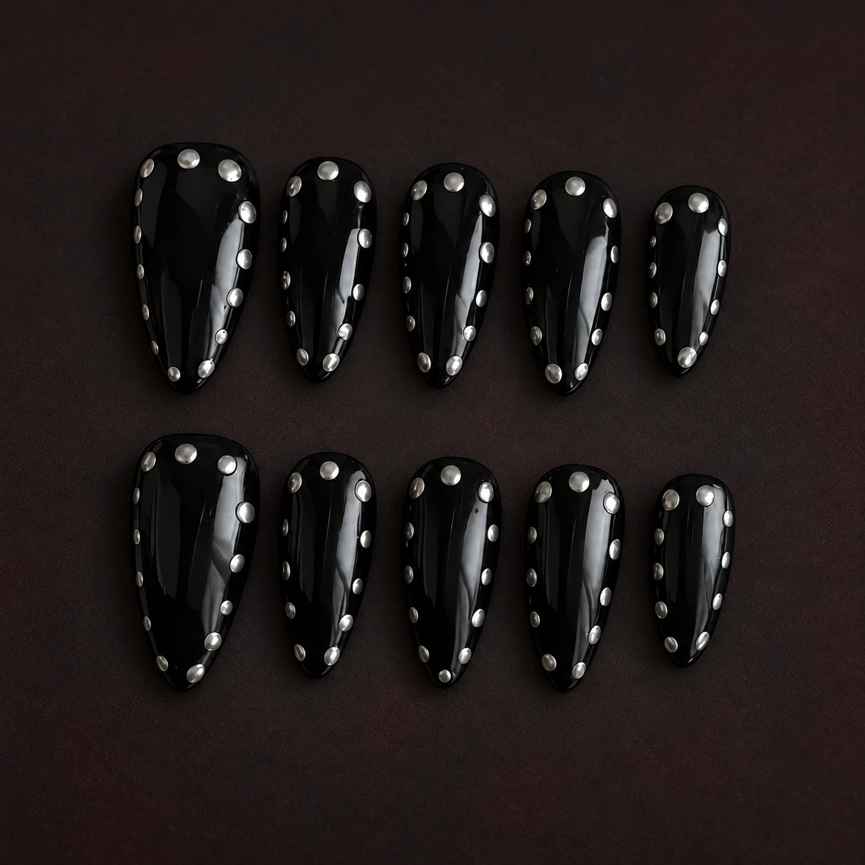 Noir Halo black press-on nails with silver stud details; AI-styled product photograph